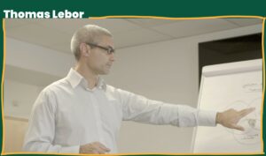 A man (Thomas Lebor) pointing at a white board explaining a leadership concept